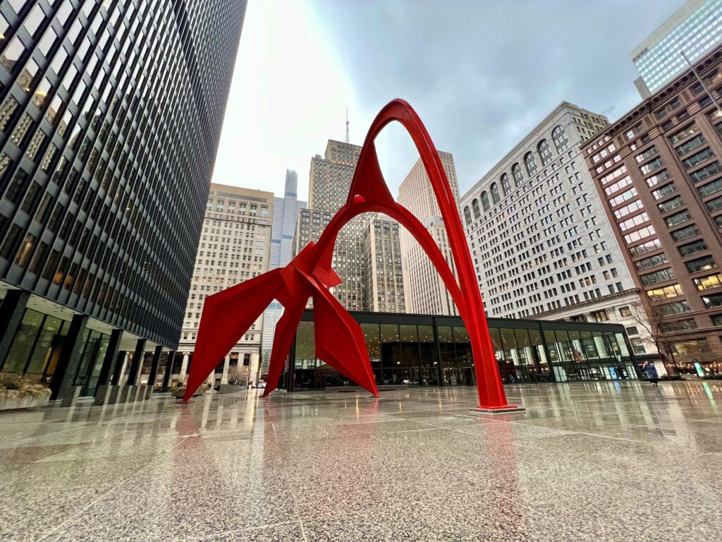 photo of a red sculpture in chicago called "flamingo". it is surrounded by office buildings