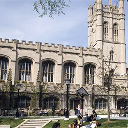 photo of a university with students sitting on lawn