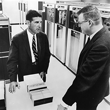 black and white photo of james h. lorie talking to lawrence fisher in an office setting